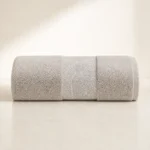 Serenity Textured Towel in beige, rolled, with a woven leaf-pattern band